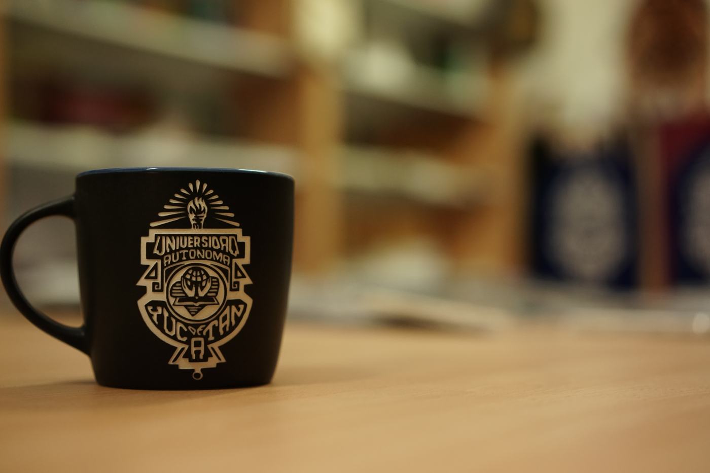 Taza negra con el escudo de la Universidad Autónoma de Yucatán